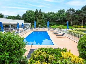 - une piscine avec des parasols et des chaises bleus dans l'établissement Novotel Rennes Alma, à Rennes