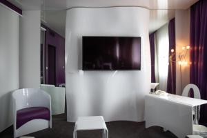 Habitación con TV en la pared, mesa y sillas. en Zenitude Hôtel Résidences Bassin d'Arcachon, en La Teste-de-Buch