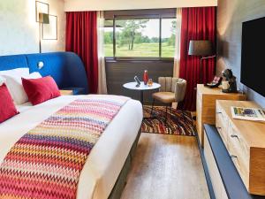 
a room with a bed, table, and window at Golf du Médoc Resort Bordeaux - MGallery in Le Pian-Médoc
