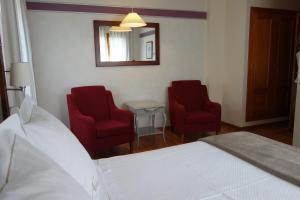 a bedroom with two red chairs and a bed and a mirror at Hotel Abetos in Torla-Ordesa