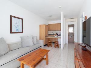 HomeForGuest Apartamento 15 con terraza y piscina en Corralejo في كوراليخو: غرفة معيشة مع أريكة وطاولة