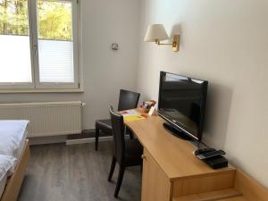 Habitación con escritorio, TV y cama. en Hotel Wintersmühle, en Bielefeld