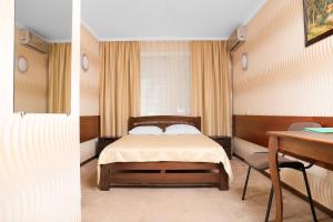 a bedroom with a bed and a table and a desk at Green City Hotel in Mykolaiv