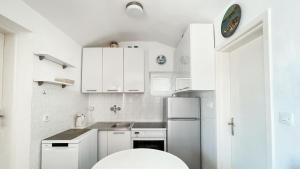 una cocina blanca con armarios blancos y fregadero en Apartments Antonela, en Sveti Stefan