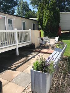 a porch with a white fence and chairs and flowers at Stunning deluxe 3 bedroomed caravan with CH, DG and decking. in Blackpool