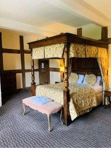 a bedroom with a large canopy bed with a pink bench at Telford Madeley Court Hotel in Telford