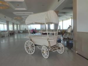 an old white carriage in a room with tables at Casale Certosa in Pavona
