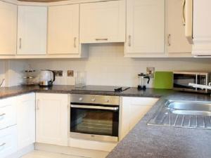 a kitchen with white cabinets and a stove top oven at Luxurious KC House in Dungannon