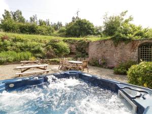 a hot tub in a yard with a table and chairs at Wheelbarrow Castle in Stoke Prior