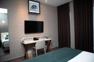 a hotel room with a desk with a television on the wall at THE PALMS Luxury Boutique Hotel in Dakar