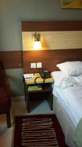 een slaapkamer met een bed en een bureau met een telefoon erop bij Springfield Guest House Rawalakot in Rāwala Kot