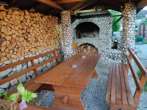 a wooden table and bench in front of a stone oven at Apartman Rakovica in Sarajevo