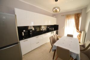 a kitchen with white cabinets and a table with chairs at Apartments Stoudios Georgias in Arkoudi