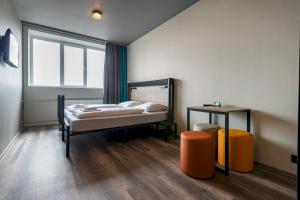 a bedroom with a bed, desk, chair and a window at a&o Copenhagen Sydhavn in Copenhagen