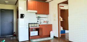済州市にあるJun Houseのキッチン(木製キャビネット、白い冷蔵庫付)