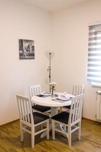 a white dining room table with three chairs and a table at Modesty Zlatar in Nova Varoš