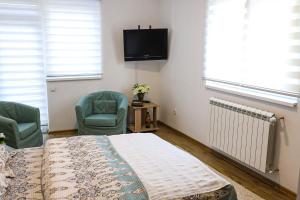 a bedroom with a bed and two chairs and a tv at Modesty Zlatar in Nova Varoš
