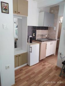 a kitchen with white cabinets and a wooden floor at Apartmani KiKi in Utjeha