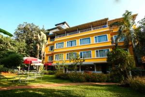 a large yellow building with a red umbrella and chairs at Lake View Resort Lonavala in Lonavala