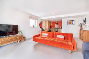 an orange couch in a living room with a television at City Apartments - John Walker House in York