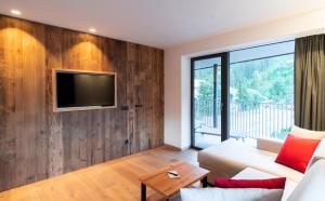 een woonkamer met een bank en een tv aan een houten muur bij Chalet Insignis in Santa Cristina in Val Gardena