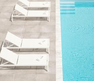 a white bench next to a swimming pool at Cove Suites Apartment in Iraklitsa