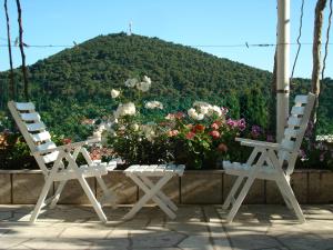 two white chairs sitting next to a table with flowers at Rooms and Apartment Nike in Dubrovnik