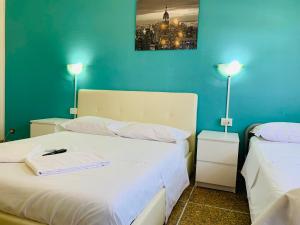 a room with two beds and a blue wall at Pearl Pisa guest house in Pisa