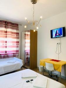 ピサにあるPearl Pisa guest houseのベッド2台、テーブル、テレビが備わる客室です。