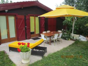 a patio with a table and a yellow umbrella at Locatlantique in Aytré