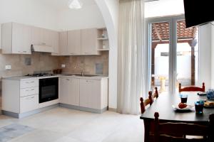 cocina con armarios blancos, mesa y comedor en Salaqua Bed and Breakfast, en Torre Mozza