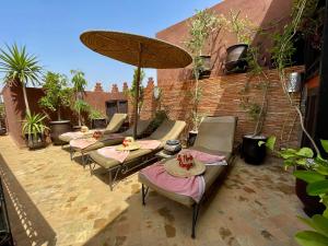 un grupo de sillas y una sombrilla en un patio en Riad La Porte Rouge, en Marrakech