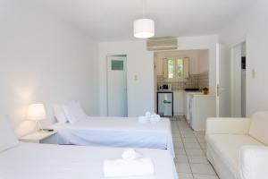 - un salon blanc avec 2 lits et un canapé dans l'établissement Tzane Apartments, à Chrissi Akti