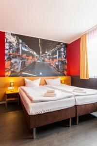 a bedroom with two beds with a painting on the wall at Altora Eisenbahn Themenhotel in Wernigerode