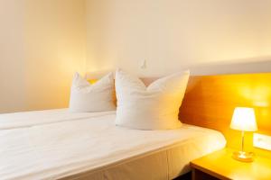 1 dormitorio con 1 cama con sábanas y almohadas blancas en Altora Eisenbahn Themenhotel, en Wernigerode