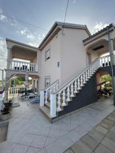 a white house with a staircase and a patio at Apartmani Mirela in Krk