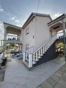 a white house with a staircase and a patio at Apartmani Mirela in Krk