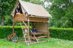 two people sitting in a tree house with a bike at Camping de l'Hippodrome in Sablé-sur-Sarthe