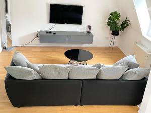 Charming Central Apartments في بادن بادن: أريكة سوداء مع وسائد في غرفة المعيشة