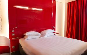 una camera da letto rossa con letto e cuscini bianchi di Zenitude Hôtel Résidences Bassin d'Arcachon a La Teste-de-Buch
