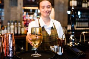 a woman standing behind a bar with a glass of wine at The Seaburn Inn - The Inn Collection Group in Sunderland