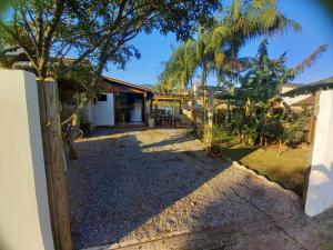 an open gate to a house with palm trees at Loft praia Porto Belo in Porto Belo