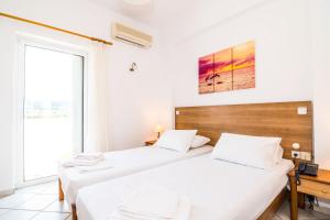 two beds in a room with a window at Thalassa Apartments in Kissamos