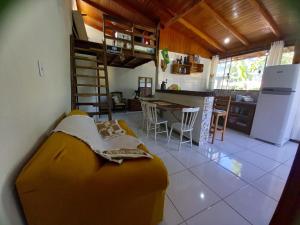 a living room with a yellow couch and a kitchen at Loft praia Porto Belo in Porto Belo