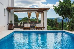 a swimming pool with two chairs and a pergola at Holiday cottage Kokic in Donji Proložac