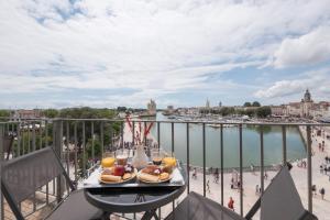 a table with food on a balcony with a view of the water at Tour de Nesle La Rochelle Vieux Port 3 etoiles in La Rochelle