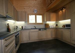 a kitchen with wooden cabinets and a clock on the wall at Chalet Forget me not in Gryon