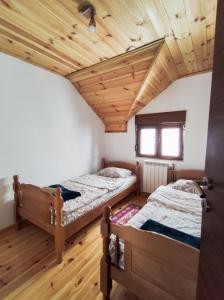 two beds in a room with wooden ceilings at Apartment Winter Star in Kolašin