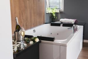a bathroom with a tub with a bottle of wine at Relaxroom in Reda