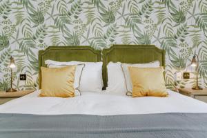 1 dormitorio con 1 cama con sábanas blancas y almohadas amarillas en Bel and The Dragon at Red Lion Wendover, en Wendover